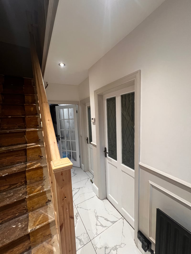 Completed hallway showing a new white interior door with decorative glass panels