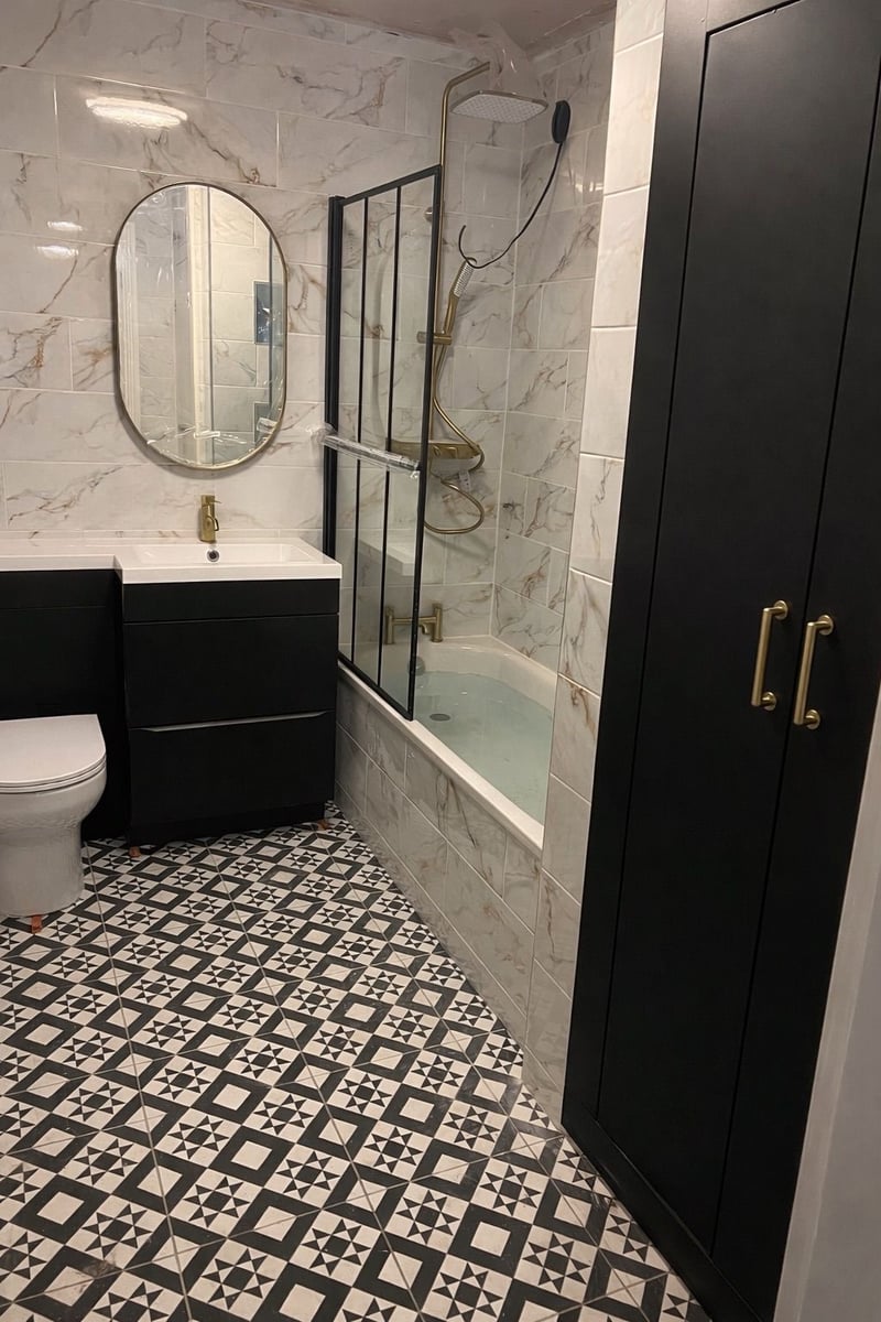 Completed bathroom with marble-effect tiling, black vanity unit, brass fittings and patterned floor tiles