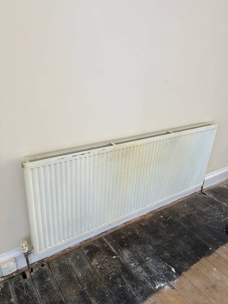 Old discoloured panel radiator on a hallway wall before painting